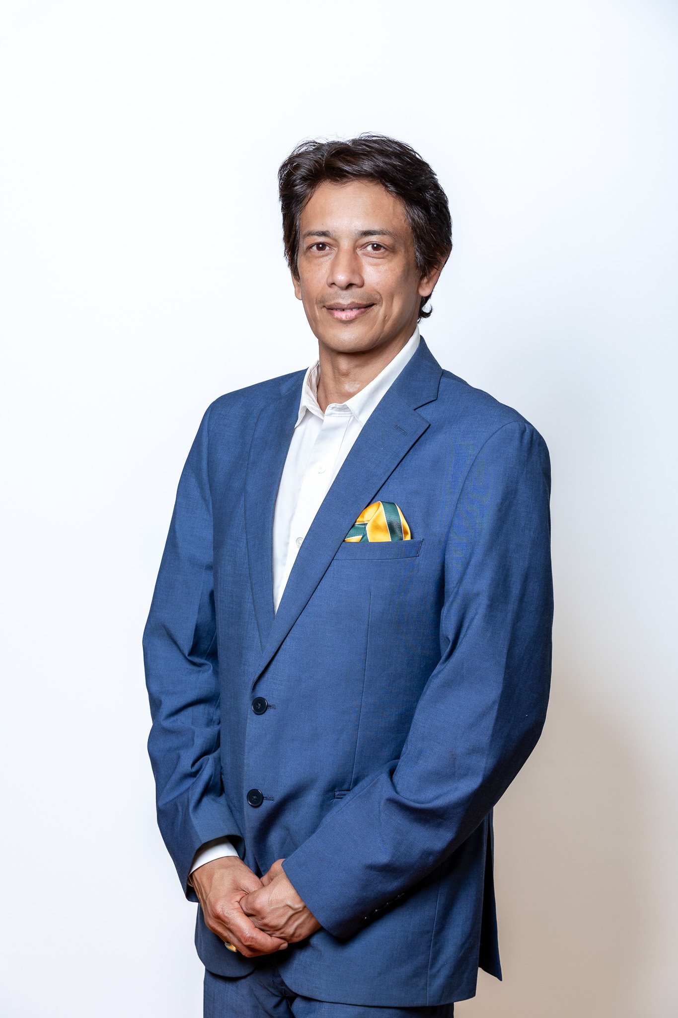 Executive headshot in a blue suit against a white backdrop